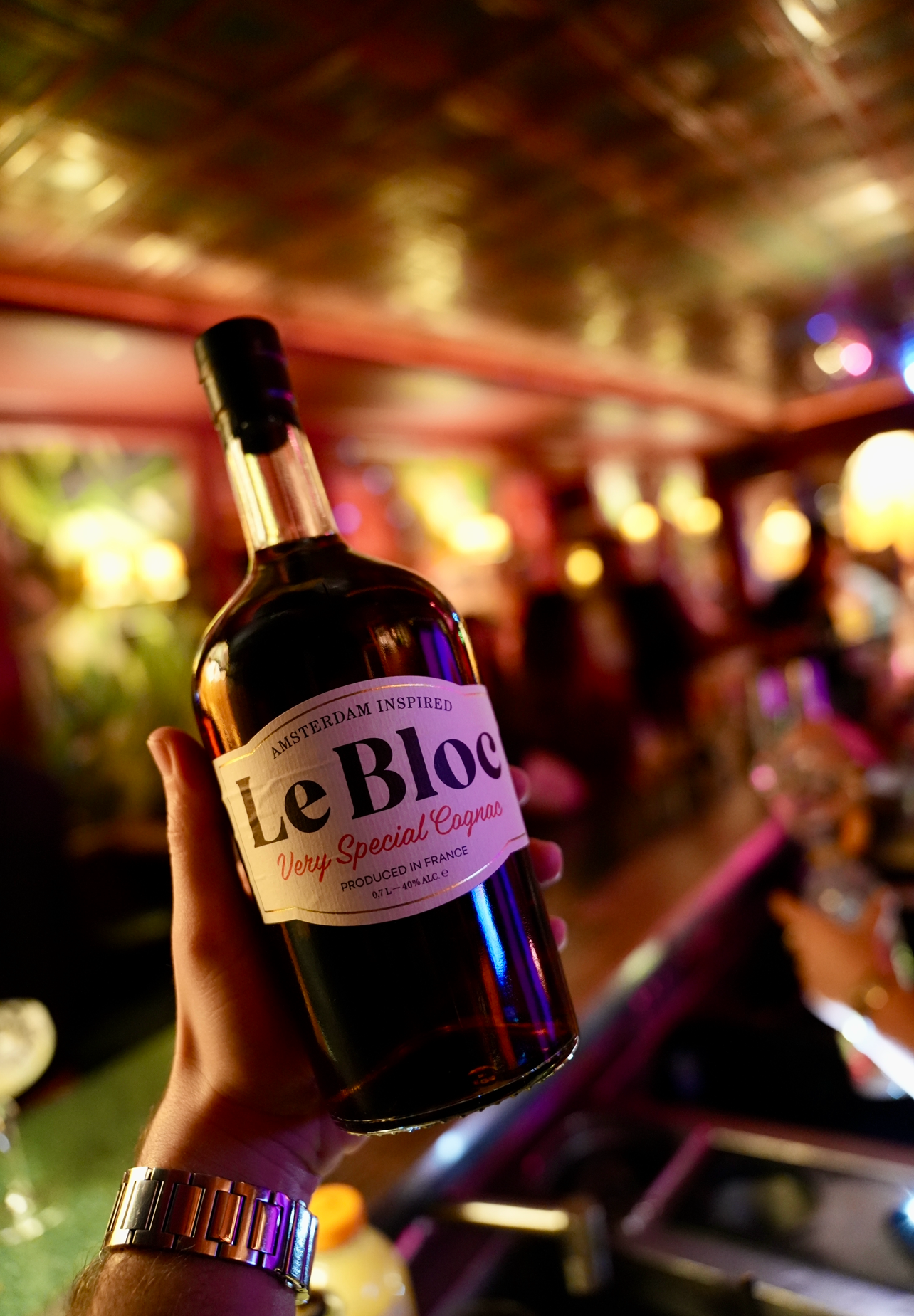 Bottle of Le Bloc brandy held by a person in a bar setting
